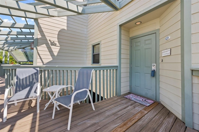 property entrance featuring a wooden deck and a pergola