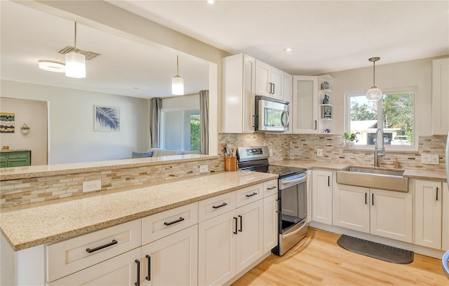 kitchen featuring stainless steel appliances, light stone countertops, sink, and decorative light fixtures