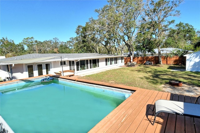 view of swimming pool with a wooden deck, a fire pit, and a lawn