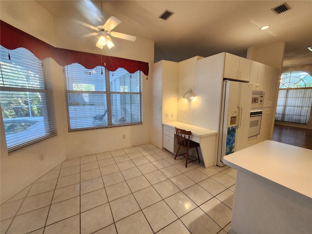 kitchen with light tile patterned floors, white appliances, white cabinetry, and ceiling fan