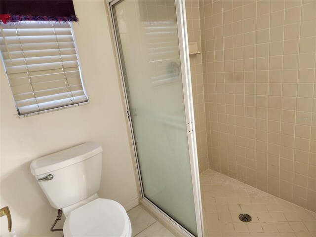 bathroom featuring tile patterned flooring, an enclosed shower, and toilet