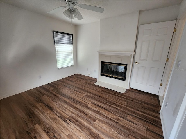 unfurnished living room featuring a fireplace, ceiling fan, and dark wood-type flooring