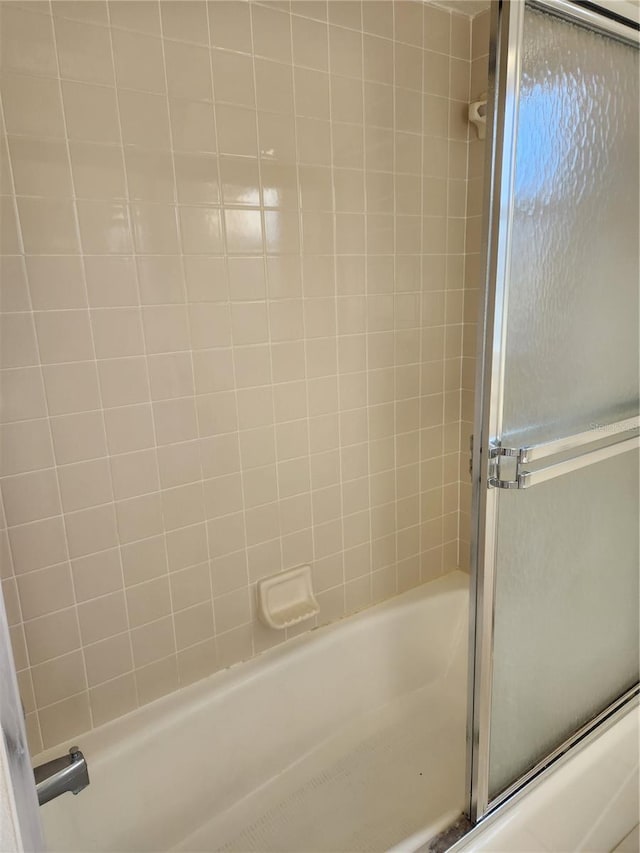 bathroom featuring combined bath / shower with glass door