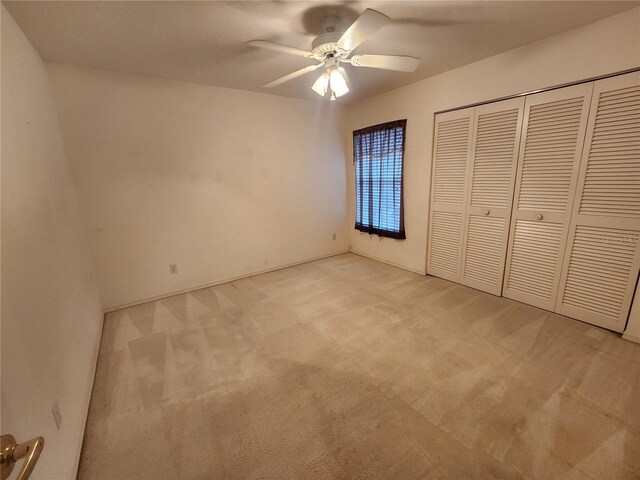 unfurnished bedroom featuring ceiling fan, light carpet, and a closet