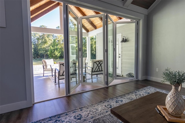 doorway to outside with dark hardwood / wood-style floors and vaulted ceiling with beams