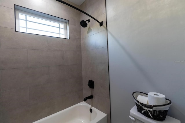 bathroom with toilet and tiled shower / bath