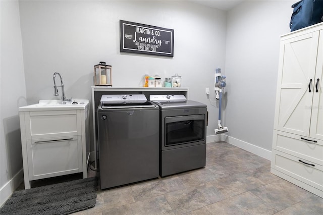 clothes washing area with cabinets, washer and clothes dryer, and sink