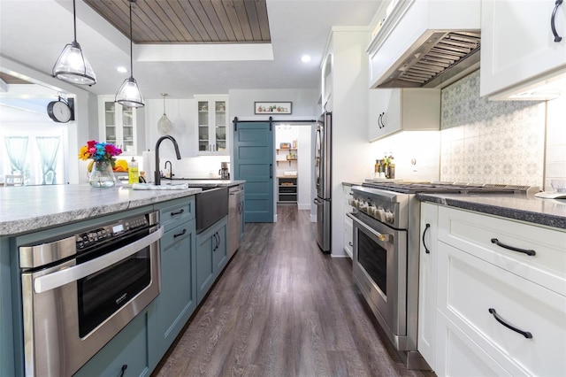 kitchen with premium range hood, appliances with stainless steel finishes, pendant lighting, white cabinets, and a barn door