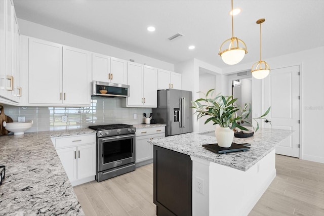 kitchen featuring white cabinetry, decorative backsplash, hanging light fixtures, a center island, and stainless steel appliances