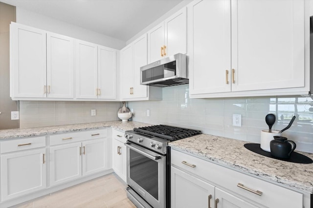 kitchen featuring white cabinetry, backsplash, light stone countertops, and appliances with stainless steel finishes