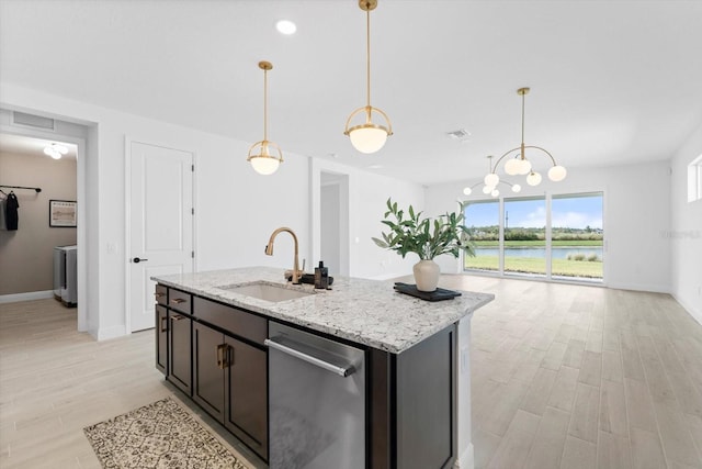 kitchen with pendant lighting, sink, a water view, light stone counters, and a center island with sink