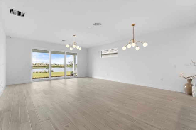 empty room with a water view, a chandelier, and light wood-type flooring