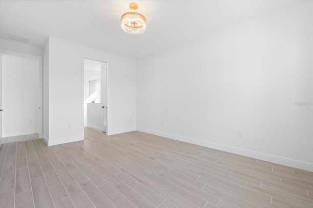 empty room featuring light hardwood / wood-style flooring and a chandelier