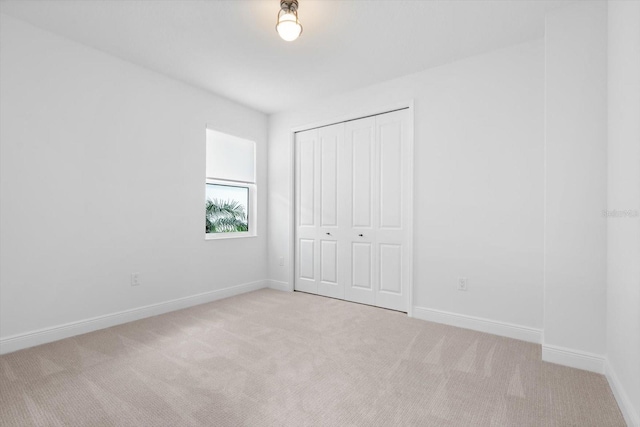 unfurnished bedroom with light colored carpet and a closet