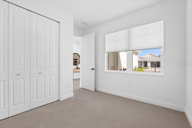 unfurnished bedroom with light colored carpet and a closet