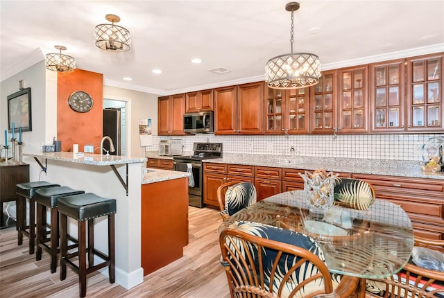 kitchen with kitchen peninsula, light stone countertops, pendant lighting, an inviting chandelier, and appliances with stainless steel finishes