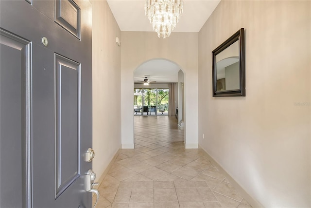 hallway with light tile patterned floors and an inviting chandelier