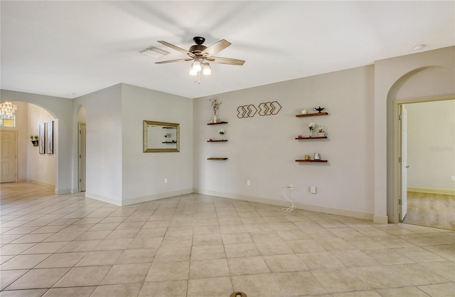 empty room featuring light tile patterned flooring and ceiling fan with notable chandelier