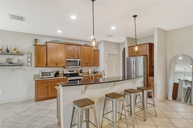 kitchen featuring a kitchen island, stainless steel appliances, light tile patterned flooring, a kitchen bar, and decorative light fixtures