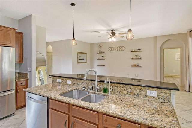 kitchen featuring a center island with sink, sink, light tile patterned floors, and stainless steel refrigerator