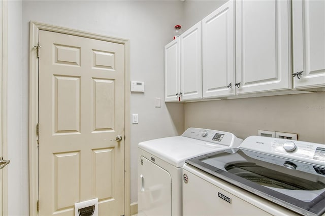 clothes washing area featuring cabinets and washing machine and clothes dryer