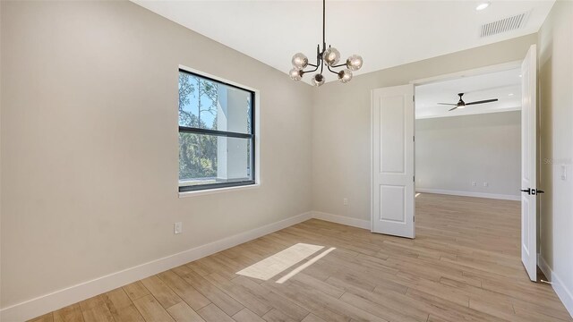 empty room with light wood-type flooring and ceiling fan with notable chandelier