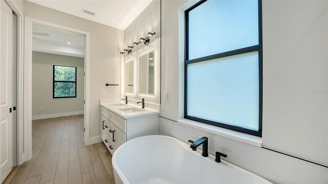 bathroom with vanity, a tub to relax in, and hardwood / wood-style flooring