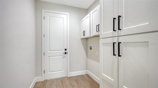 clothes washing area featuring light hardwood / wood-style floors, washer hookup, and cabinets