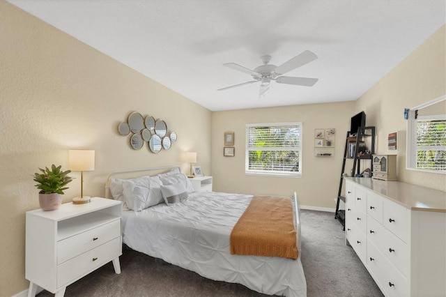 bedroom featuring multiple windows, ceiling fan, and dark colored carpet