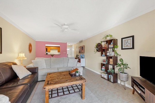 living room featuring ceiling fan, light tile patterned floors, and crown molding