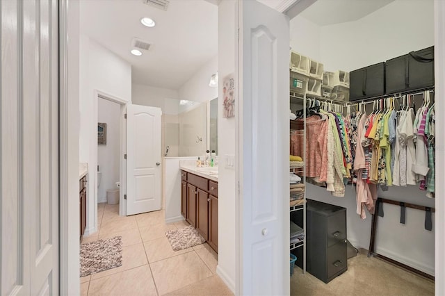 bathroom with tile patterned floors, a tile shower, and vanity