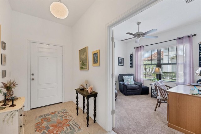 foyer entrance with light carpet, ceiling fan, and light tile patterned floors