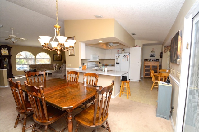 dining space featuring lofted ceiling, a textured ceiling, light colored carpet, ceiling fan with notable chandelier, and visible vents