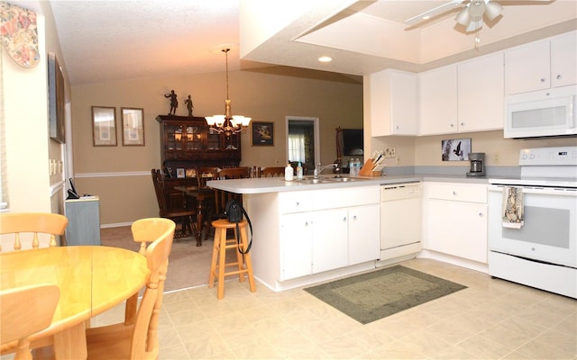 kitchen featuring pendant lighting, white appliances, lofted ceiling, kitchen peninsula, and white cabinetry