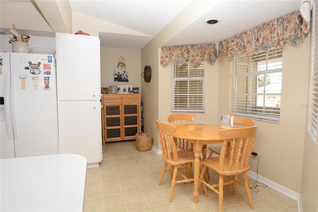 dining area featuring lofted ceiling, a textured ceiling, and baseboards