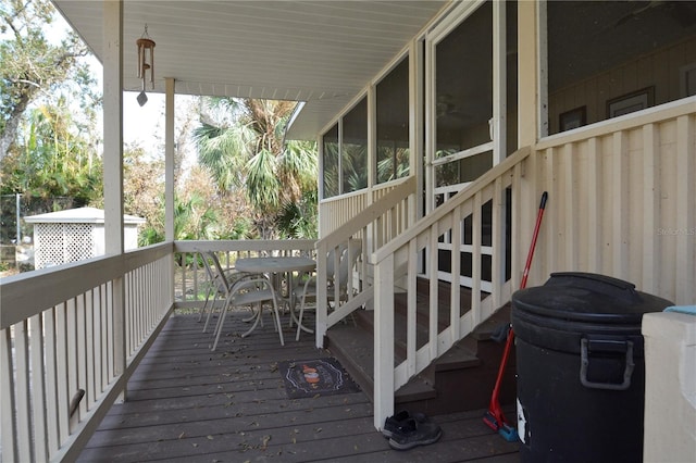 wooden deck with a sunroom and stairs