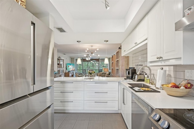 kitchen with appliances with stainless steel finishes, a notable chandelier, hanging light fixtures, white cabinets, and kitchen peninsula