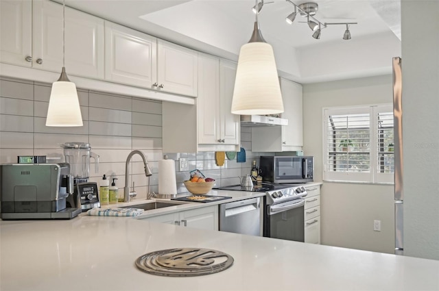 kitchen with backsplash, appliances with stainless steel finishes, pendant lighting, sink, and white cabinets