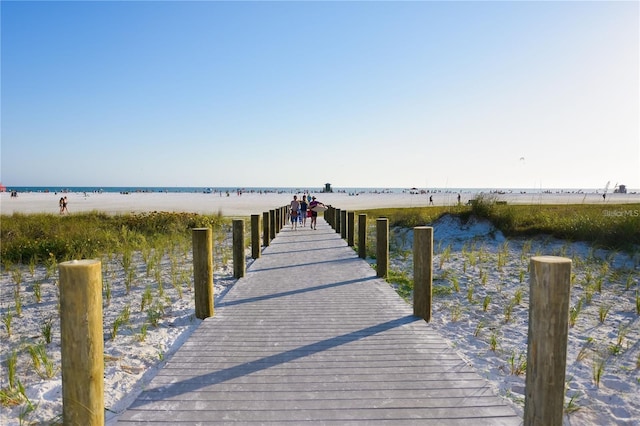 view of dock featuring a beach view and a water view