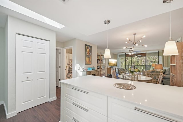 kitchen featuring dark hardwood / wood-style flooring, pendant lighting, an inviting chandelier, a skylight, and white cabinetry