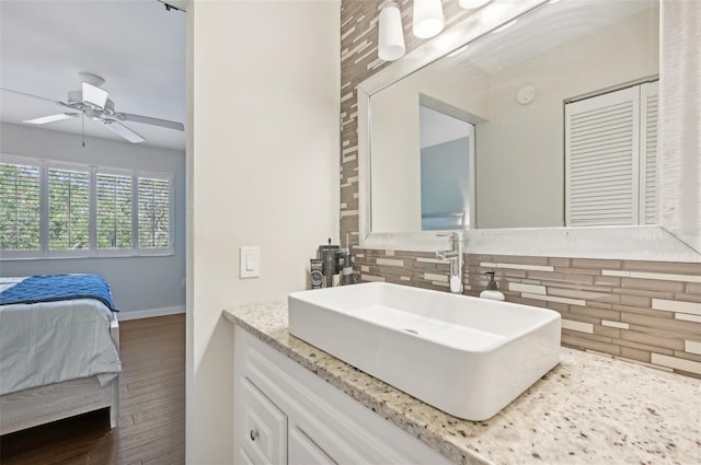 bathroom with decorative backsplash, hardwood / wood-style floors, ceiling fan, and vanity