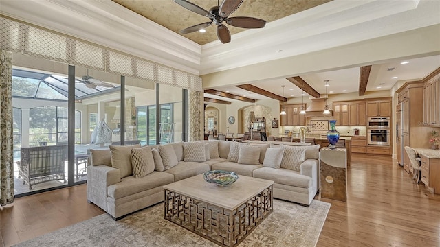 living room with ceiling fan, beamed ceiling, light hardwood / wood-style floors, and ornamental molding