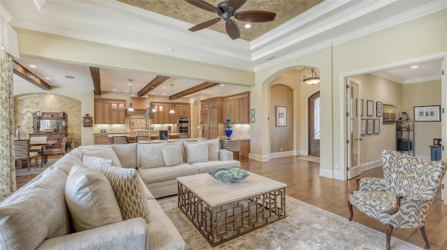 living room with ceiling fan, beamed ceiling, light hardwood / wood-style floors, and ornamental molding