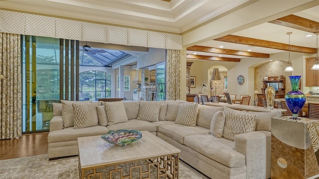 living room featuring ceiling fan, light hardwood / wood-style floors, ornamental molding, and beam ceiling