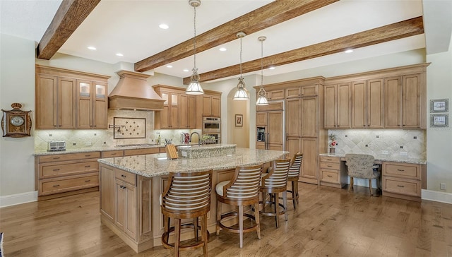 kitchen featuring custom exhaust hood, a large island with sink, decorative backsplash, dark hardwood / wood-style floors, and beam ceiling