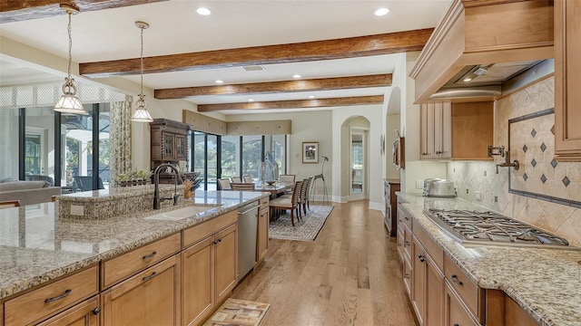 kitchen with decorative backsplash, appliances with stainless steel finishes, light wood-type flooring, sink, and hanging light fixtures