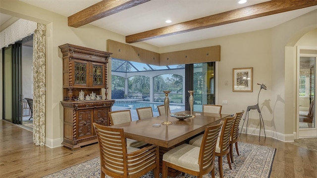 dining room with beamed ceiling, light hardwood / wood-style floors, and a wealth of natural light