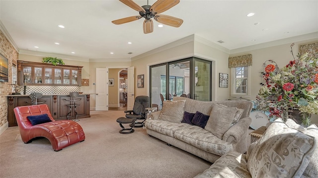 living room featuring bar, crown molding, ceiling fan, and light colored carpet