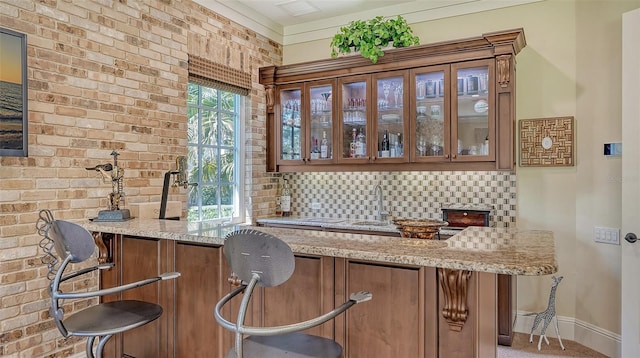 bar featuring decorative backsplash, light stone counters, and brick wall