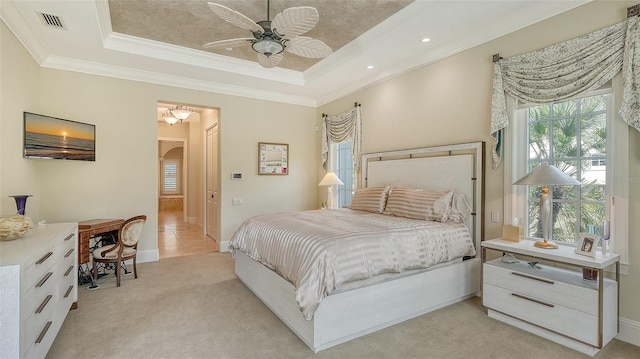 carpeted bedroom featuring ceiling fan, a raised ceiling, and ornamental molding